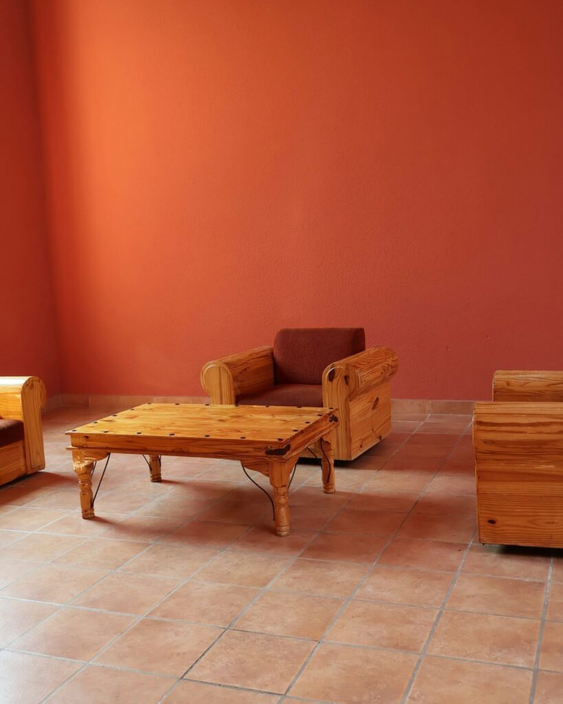 A terracotta wall with a woven chair and soft light