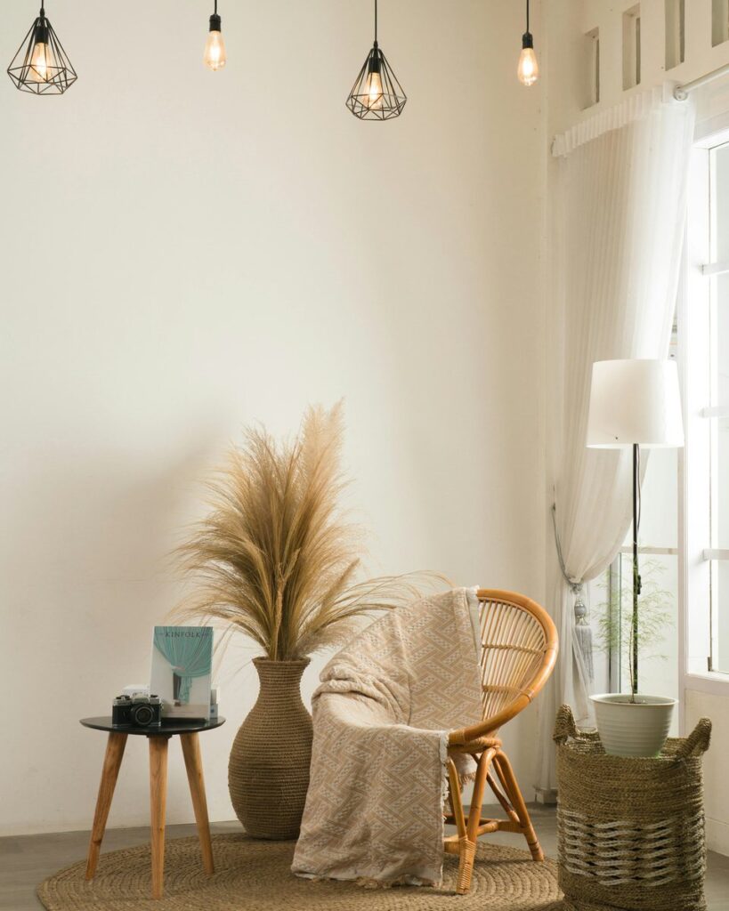 A styled corner with an accent chair, pampas grass, and a pendant lamp