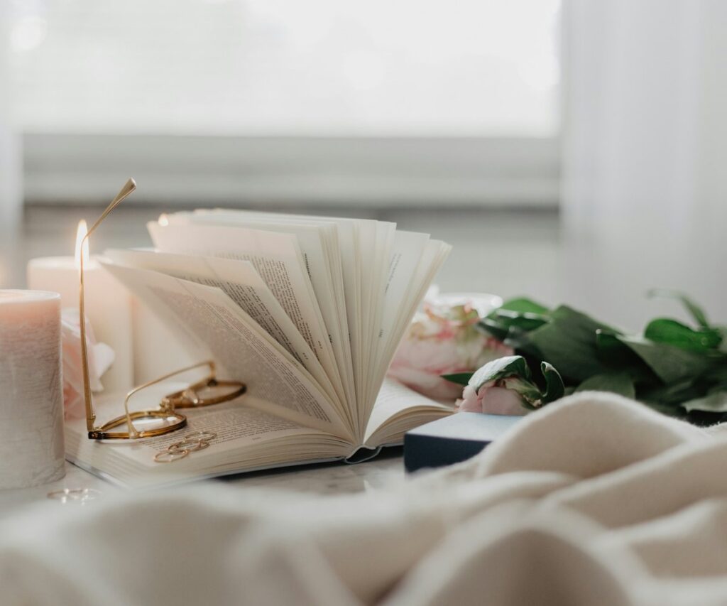 Soft blanket, candle, and greenery on a cream bed