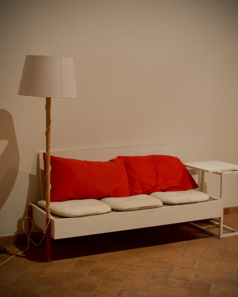 My sofa corner with a red throw, pillows, and a floor lamp in warm evening light